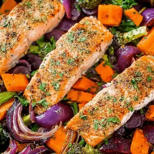 Easy One Pan Baked Salmon with Veggies 1 A vibrant one pan baked salmon with veggies dish, featuring golden salmon fillets and roasted broccoli, sweet potatoes, and red onions in a metallic pan.